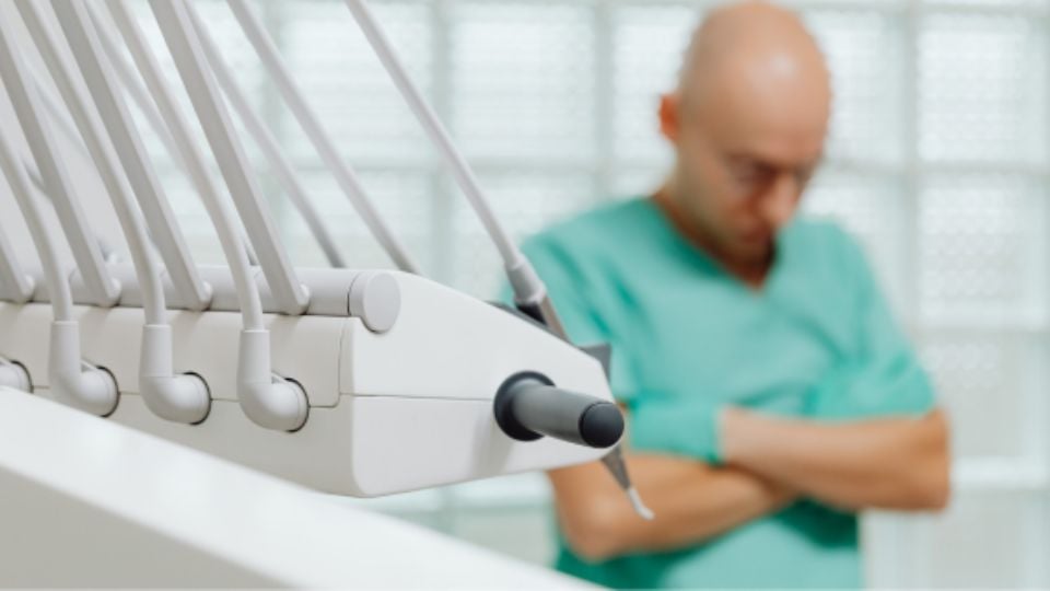 Se-muere-por-ir-al-dentista - Regios Al Cuadrado Foto De Paciente Hombre De Complexión Delgada Usando Bata Hospitalaria, Esperando En Sala Médica.