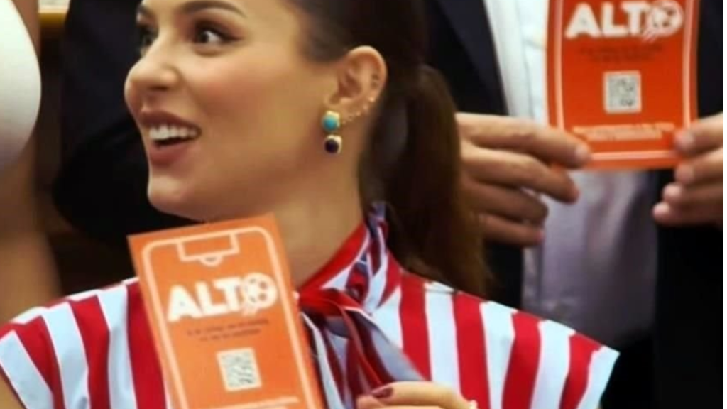 Las-tarjetas-azules-presuntamente-alteradas-por-el-partido-movimiento-ciudadano - Regios Al Cuadrado Smiling Woman in a Red-and-white Striped Outfit Holds an Orange Alt8 Card at a Promotion Event. - Regios Al Cuadrado