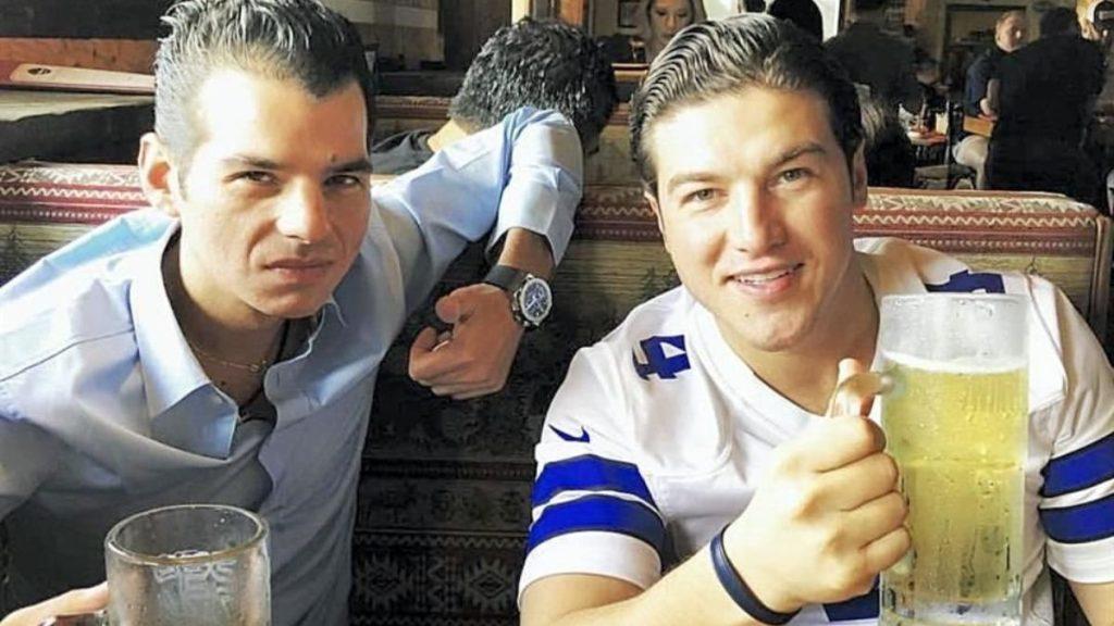 Samuel-garcía-mike-flores-90-millones-devío - Regios Al Cuadrado Two Friends at a Casual Restaurant Booth; the Man on the Right in a White Sports Jersey Holds a Large Beer and Smiles at the Camera, Giving a Thumbs Up to the Viewer. - Regios Al Cuadrado