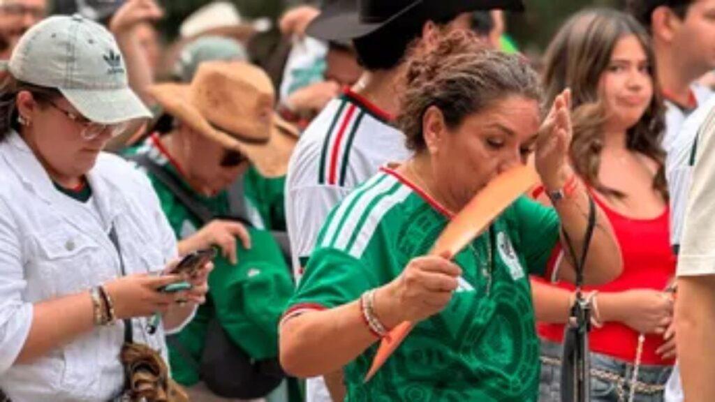 Crowd at an Outdoor Event; Woman in a Green Shirt Holds a Long Orange Bread While Others Watch. - Regios Al Cuadrado