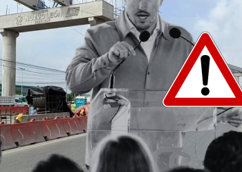 Construction Site Briefing: a Man with a Microphone Speaks to a Crowd, with a Prominent Warning Triangle in the Foreground. - Regios Al Cuadrado