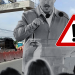 Construction Site Briefing: a Man with a Microphone Speaks to a Crowd, with a Prominent Warning Triangle in the Foreground. - Regios Al Cuadrado