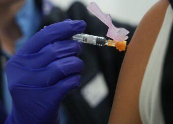 Nurse Wearing Purple Gloves Prepares a Syringe to Inject a Person's Upper Arm. - Regios Al Cuadrado