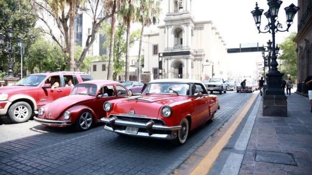 Samuel-quiere-quitar-museo-para-poner-cancha-de-pádel - Regios Al Cuadrado Vintage Red Convertibles Parked Along a City Street with Historic Buildings and Pedestrians Nearby. - Regios Al Cuadrado