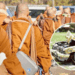 Group of Buddhist Monks in Orange Robes Standing Together; Circular Inset Shows a Yellow Car in a Severe Crash. - Regios Al Cuadrado