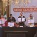 Group of Officials in a Formal Meeting Holding Signed Documents, Standing Behind a Long Table in Front of a Banner That Reads 'cero Clausuras' with a Mexican Flag Nearby. - Regios Al Cuadrado